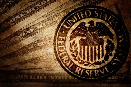 Seal of the United States Federal Reserve System on a textured background with hundred dollar bills.
