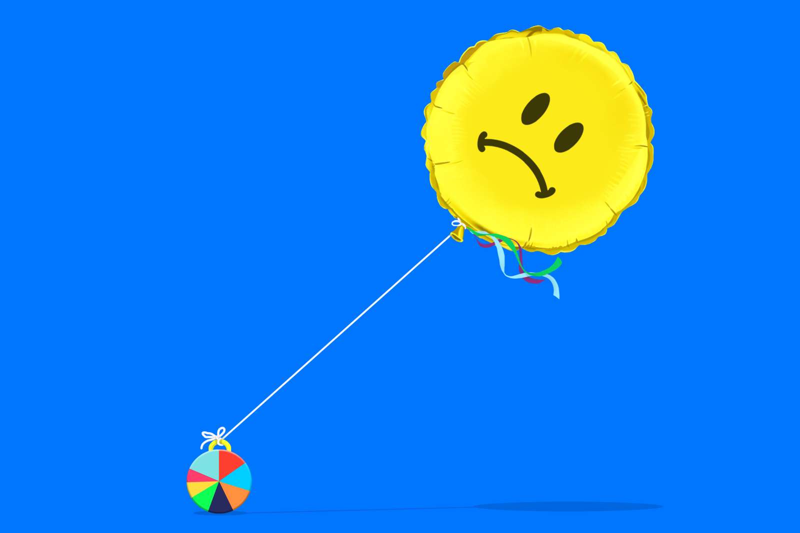 A sad face balloon is tethered to a colorful beach ball against a blue background.