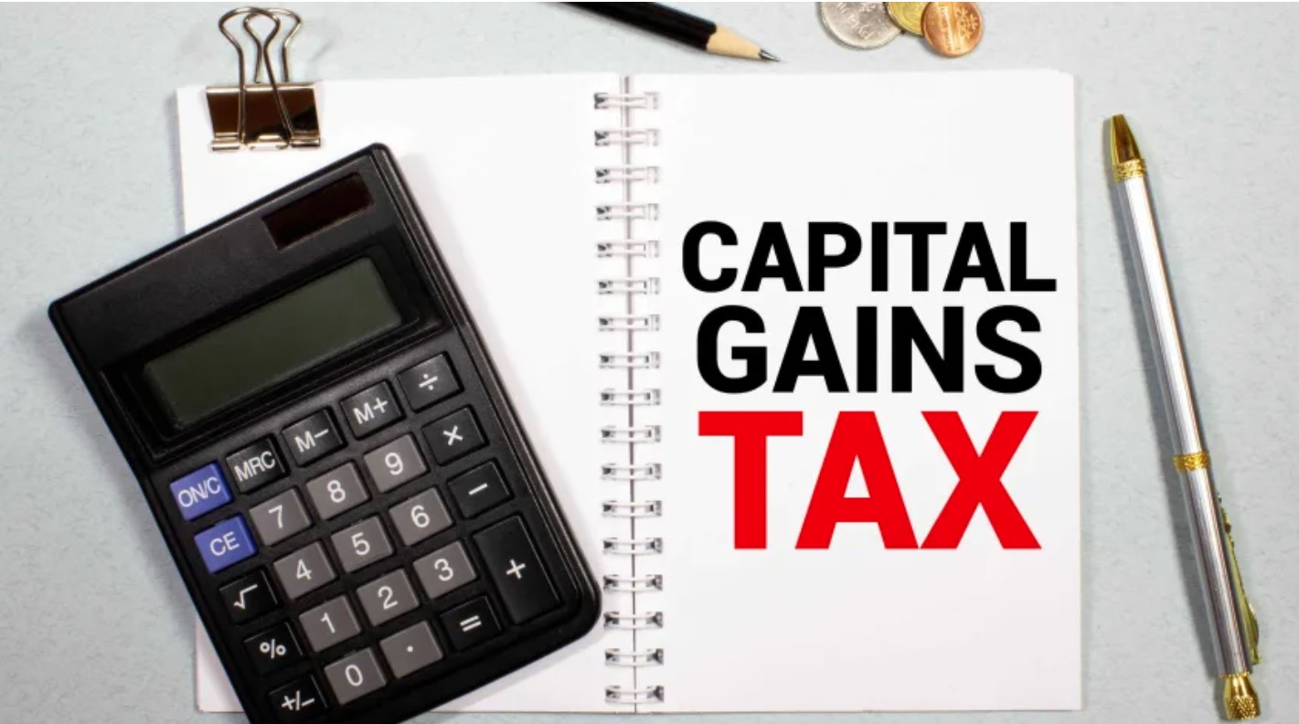 A calculator next to a notepad with 'CAPITAL GAINS TAX' written on it.